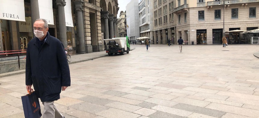 A pedestrian wearing a face mask while walking along a nearly-vacant Corso Vittorio Emanuele, the most important pedestrian street in downtown Milan. 