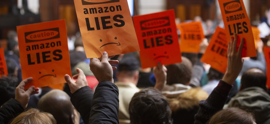 Protesters hold up signs at the second New York City Council hearing on Amazon's planned headquarters in Queens.