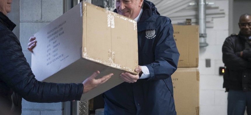 Mayor Bill de Blasio assists in picking up the United Nation's donation of 250,000 face masks. 