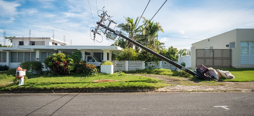 A broken telephone pole leans dangerously close to a house just outside of San Juan, Puerto Rico.