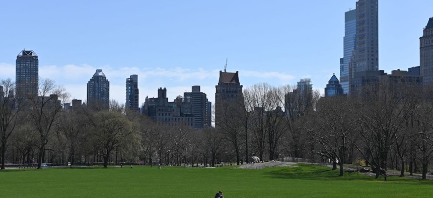 A person is sean walking throught the empty lawn of Sheep Meadow in Central Park on March 21st.