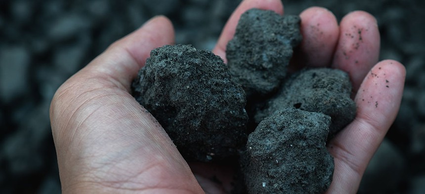 A coal miner holds lumps of coal.