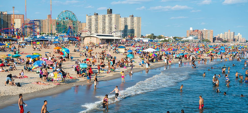 Crowds of people enjoying New York City's Coney Island beach in the midst of summer.