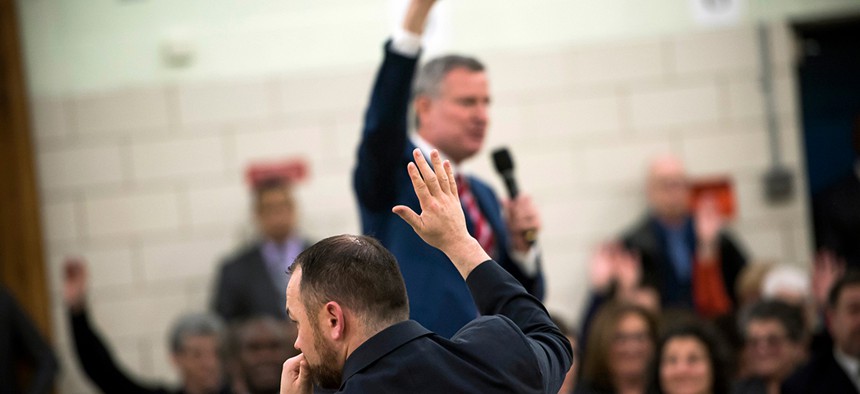 New York City Council Speaker Corey Johnson raises his hand during a town hall meeting hosted by Mayor Bill de Blasio.