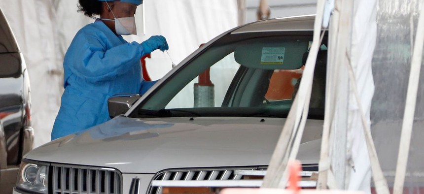 A medical technician prepares a COVID-19 test at a New York State Department of Health drive-through testing facility at Jones Beach State Park on Long Island.