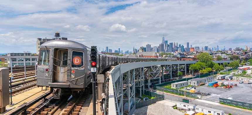 A D train entering the Smith St. station in Brooklyn with the Manhattan skyline in the background.