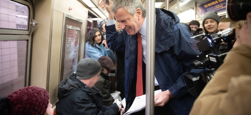 Mayor Bill de Blasio riding the subway, his homelessness plan has been broadly criticized.