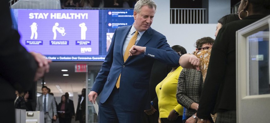 Mayor de Blasio gives out an elbow bump while taking coronavirus related calls at the 311 call center.