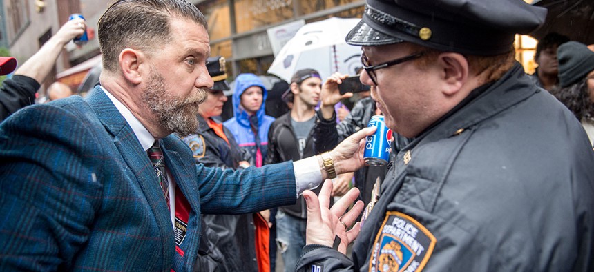 Gavin McInnes holds a pepsi can in front of an NYPD officer