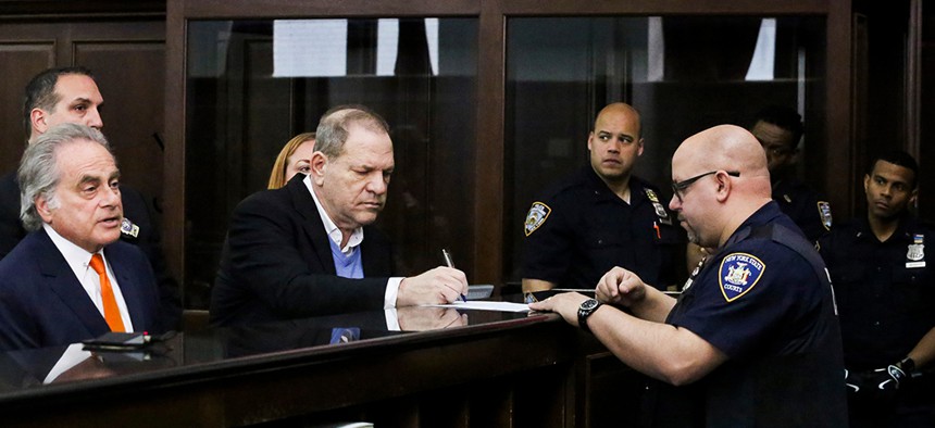 Harvey Weinstein signs papers with his attorney Benjamin Brafman [left] during his arraignment in Manhattan criminal court.