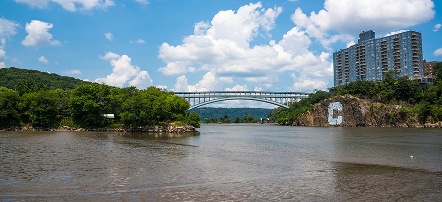 The Henry Hudson Bridge, which spans Spuyten Duyvil Creek into Inwood Hill Park. The Columbia "C" is visible along the shoreline.