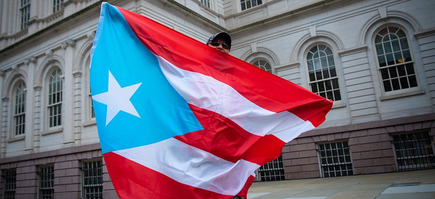 A man holds the Puerto Rican flag outside of New York City's City Hall.