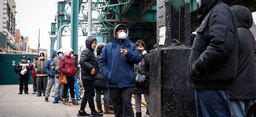 Patients wait in line outside an urgent care pharmacy while wearing personal protective equipment in Queens.