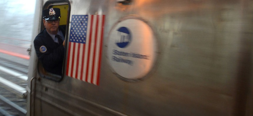 An MTA train conductor watches the platform as a train leaves the station.