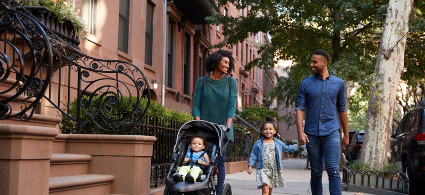 Parents with young children, one in a stroller, on a New York City street. 