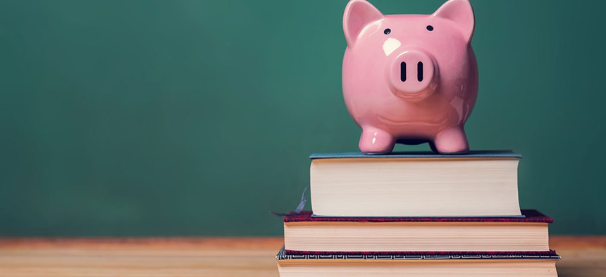 A piggy bank on top of school textbooks.