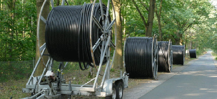 A broadband cable drum with laying trailer and other rolls with black fiber optic cables for faster Internet in rural regions like Erie County.