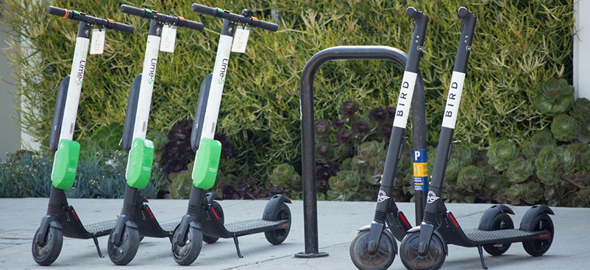 Lime and Bird e-scooters parked on the sidewalk.