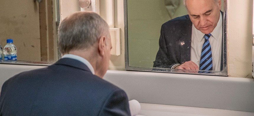 New York State Comptroller Thomas DiNapoli sitting in front of mirror looking at books