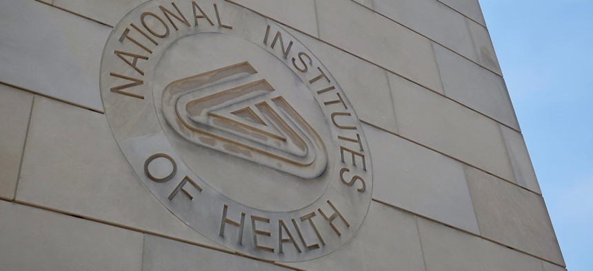 NIH NATIONAL INSTITUTES OF HEALTH sign emblem seal on gateway center entrance building at NIH campus.