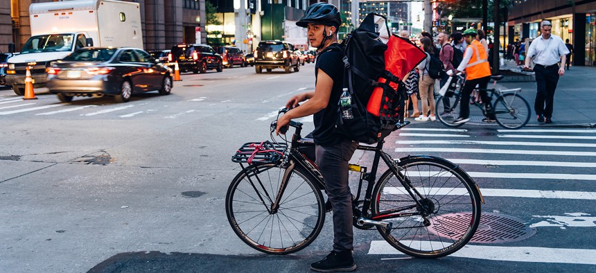 Hispanic courier on bicycle in crosswalk in New York City