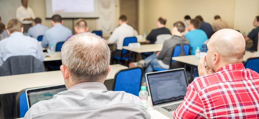 People sit in meeting with computers in classroom.