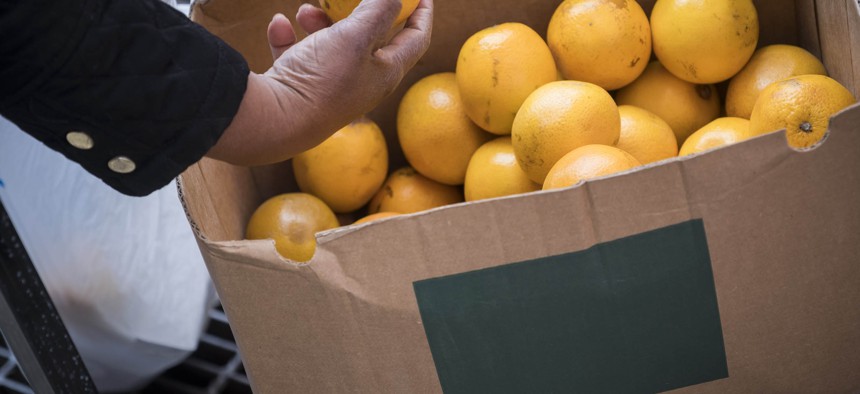 Hand picks up an orange.