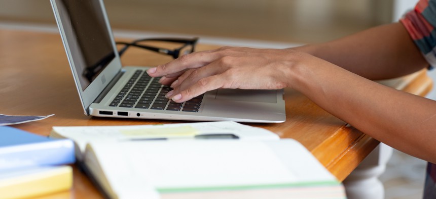 Person using laptop with notes spread around.