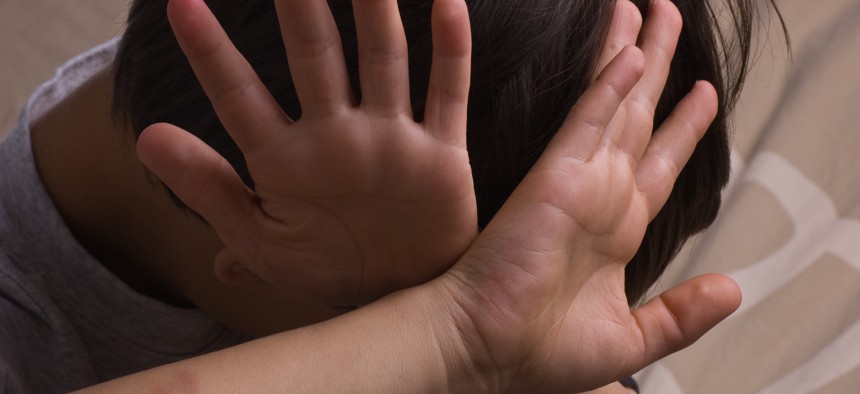 Child covering face with hands. 