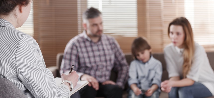 Woman sits with notepad in front of a father, small child and mother. 