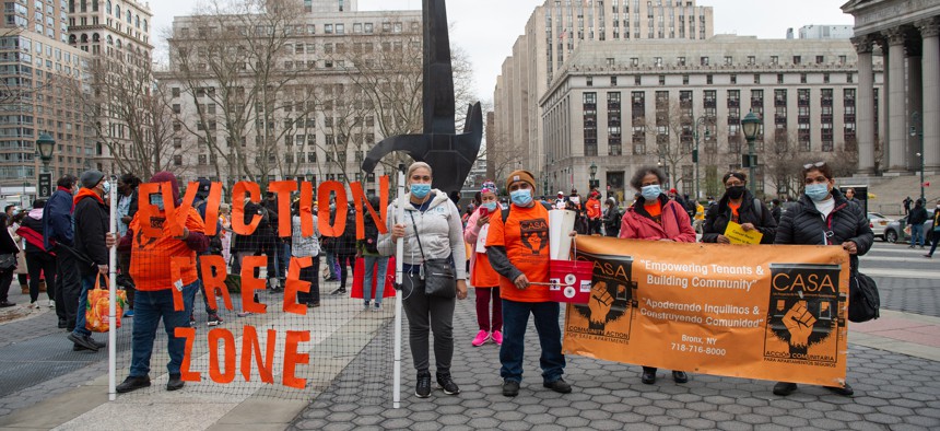 People hold up a sign that says "Eviction Free Zone" at protest.