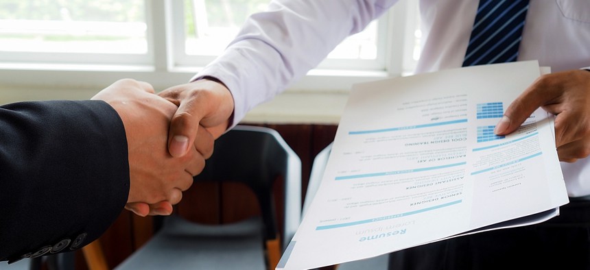 Person shakes hands with someone holding a resume.