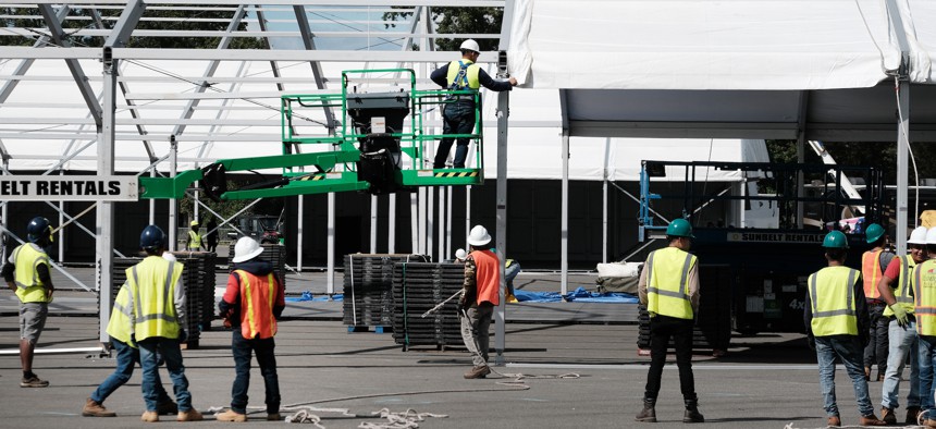 Workers began construction on a tent facility at Orchard Beach in the Bronx last week. Rain caused flooding in the parking lot over the weekend.