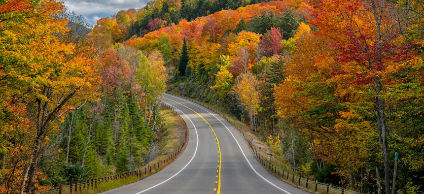 A view of autumn trees along a curve in the road along Highway 3 in the Adirondacks near Saranac Lake.