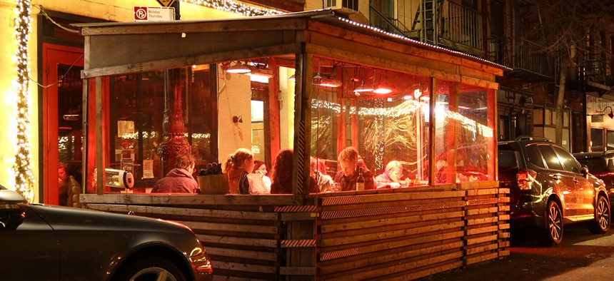People eat dinner in an outdoor sidewalk shed at a restaurant on Bedford Street in Greenwich Village on December 17, 2021 in New York City.