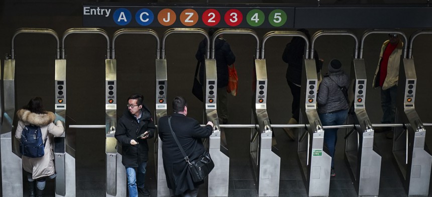 Customers move through the turnstiles at the Fulton Center subway station.