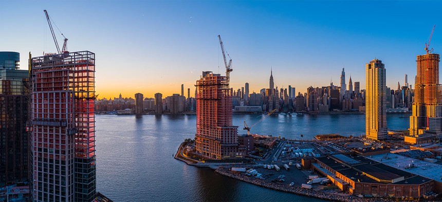 New construction rises on the waterfront of the East River in Greenpoint, Brooklyn, and Hunters Point, Queens, around Newtown Creek, with the Manhattan skyline in the background.