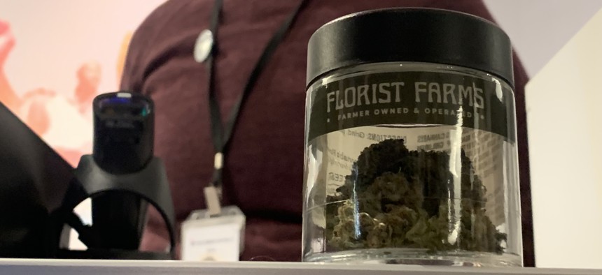 Britt Bruckner, assistant manager at Housing Works Cannabis Co. in Manhattan, displays a jar of Florist Farms marijuana for sale at the dispensary Thursday.