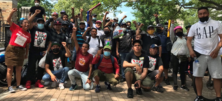 Food delivery workers raise their fists and shout "si se puede!" as they gather on June 20, 2021 to organize for better working conditions in the Washington Heights section of New York City.