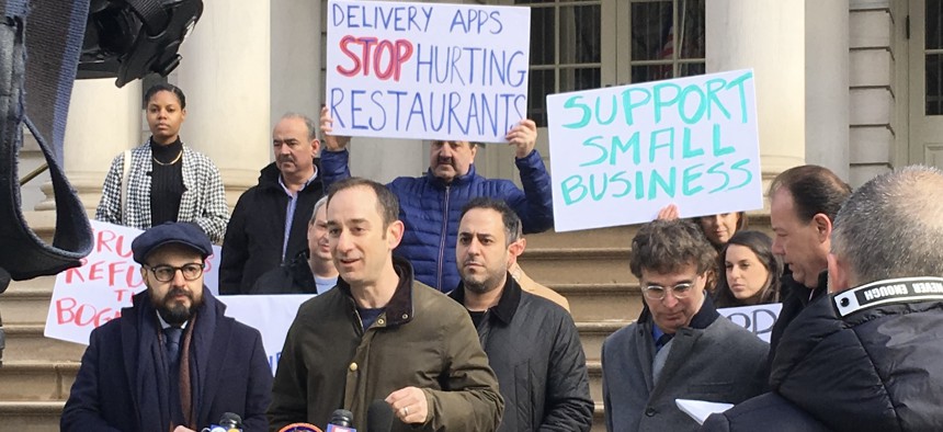 Flanked by Council Member Francisco Moya (left), NYC Hospitality Alliance executive director Andrew Rigie speaks outside City Hall at a demonstration in favor of delivery fee caps in February 2020.