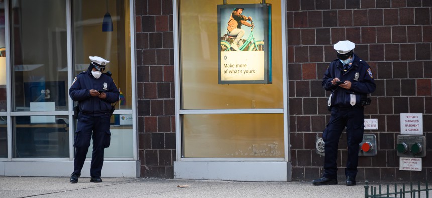 NYPD officers use their phones in Kips Bay, Manhattan, on April 15, 2020.