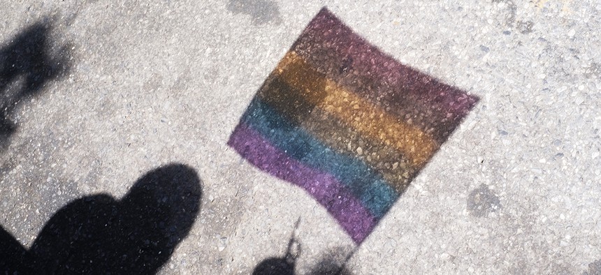 A pride flag is reflected in the pavement during the Queens Pride Parade