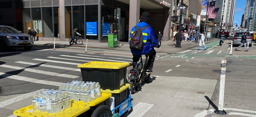 An e-bike delivery person crosses a Midtown Manhattan intersection. 