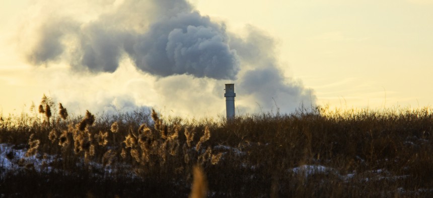 An industrial smokestack towers over a field in Syracuse, NY.