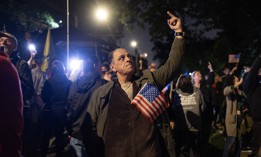 A man protesting the arrival of migrants in New York city flips off an NYPD helicopter.