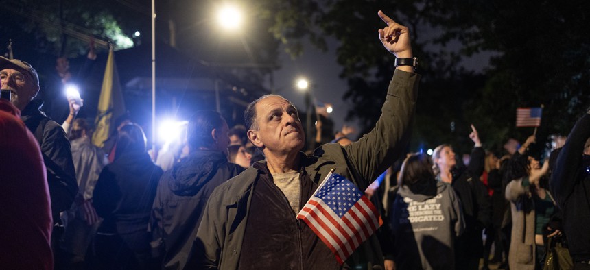 A man protesting the arrival of migrants in New York city flips off an NYPD helicopter.