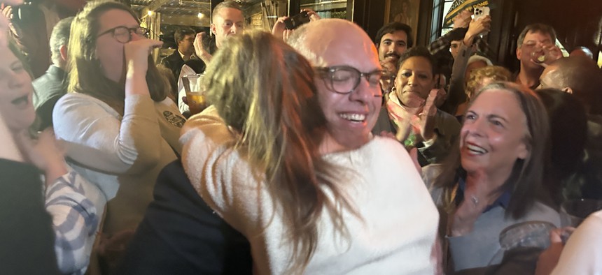 After winning re-election, City Council Member Justin Brannan embraces his wife Leigh as City Council Speaker Adrienne Adams looks on.