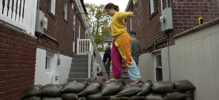 Bridget Donnelly walks on a sandbag wall outside her home as Hurricane Sandy approaches on October 28, 2012 in Rockaway Beach, Queens.