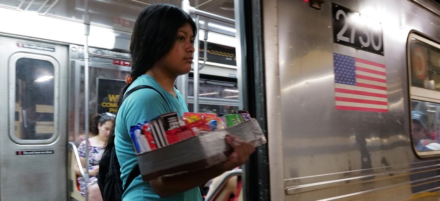 A migrant teenager sells candy on a New York City subway 