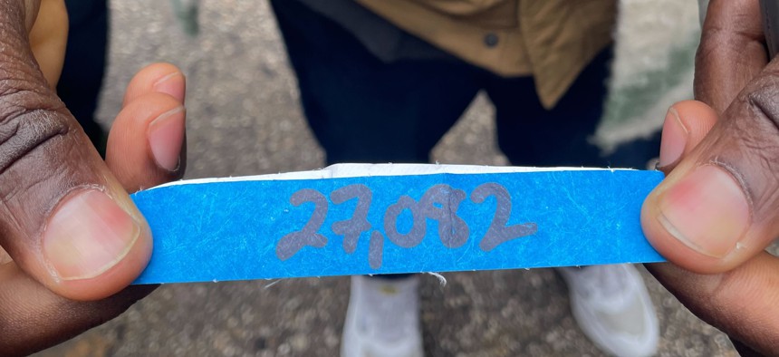 An asylum-seeker shows the wristband he received to show he’s waiting for a new shelter assignment